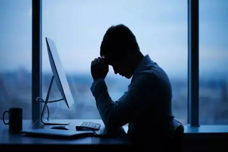 شاب يجلس حزينا ومتعبا على مكتبه أمام الكومبيوتر