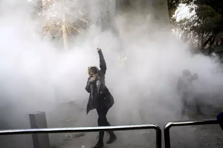 سيدة تقف في مرمى قنابل الغاز في احتجاجات إيران 2017-2018