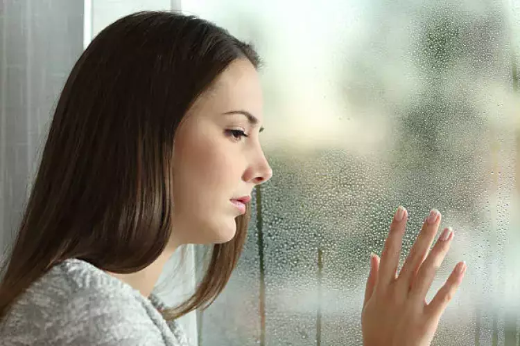 فتاة حزينة تقف أمام النافذة