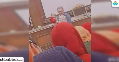 دكتور بجامعة القاهرة يحمل طفل إحدى الطالبات داخل لجنة الامتحان «فيديو»