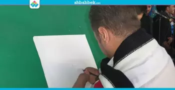 بذراعيه المبتورة.. طالب يرسم بورتريه لجابر نصار (صور)